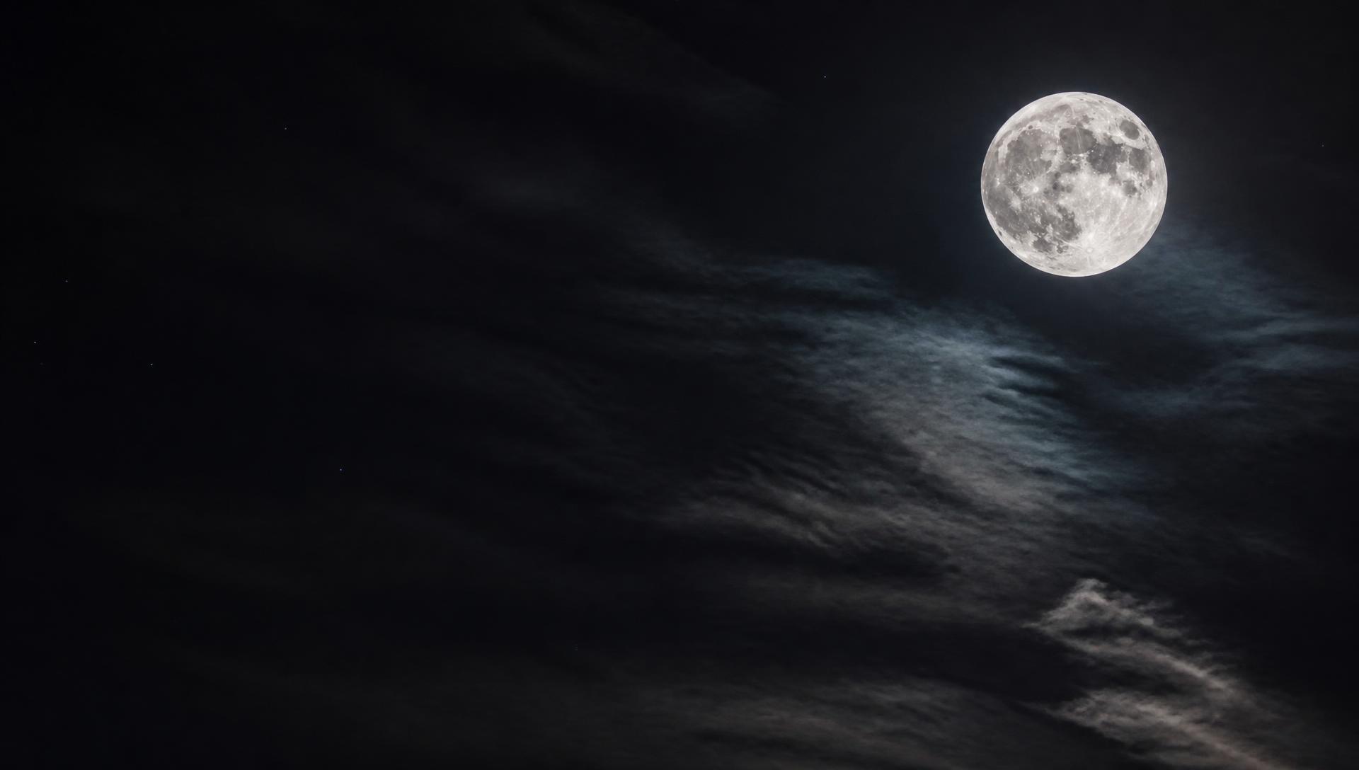 Full moon over a night sky with thin clouds